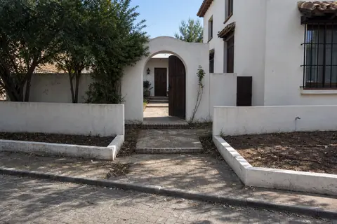 Escena simulada e ilustrativa de un patio delantero antes del concepto, con entrada simple, suelo desnudo y poca plantación